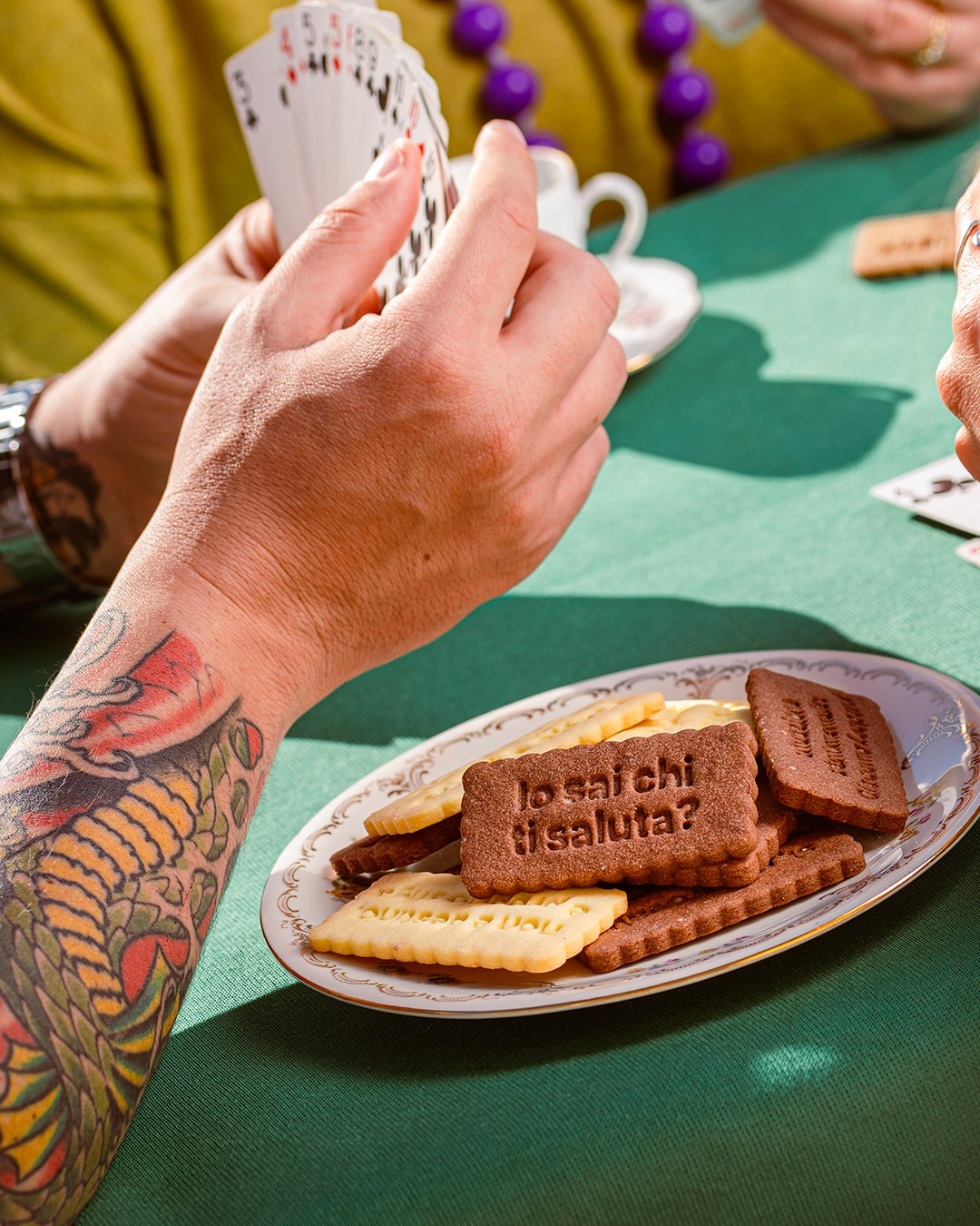 Partita a carte su un tavolo verde, tra le tazzine del caffè e un piatto di Biscotti Sinceri