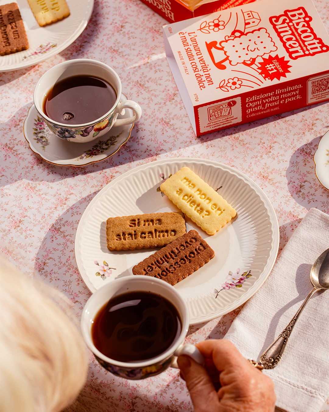 Colazione su una tovaglia a fiori: due caffè e un piattino con tre Biscotti Sinceri